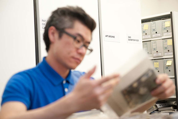 Artist Heman Chong researching the APT Archive for his artwork Asia / Pacific / Triennial 2012 / Photo: Mark Sherwood